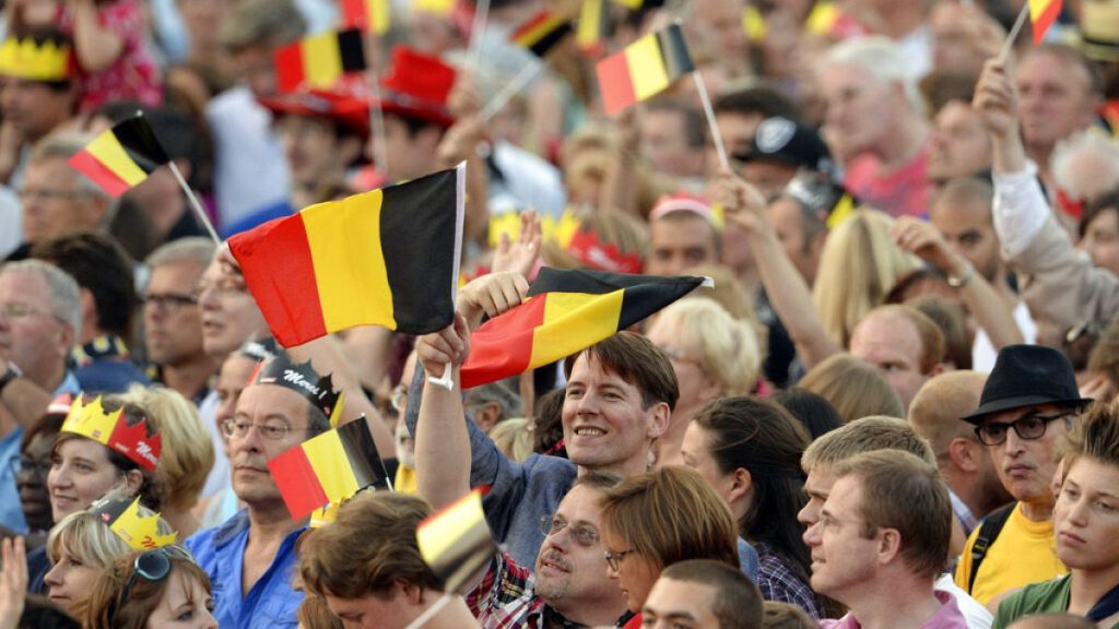 People wave Belgian flags as royal family members arrive outside of the national ball in the Marolles district of Brussels on Saturday, July 20, 2013.