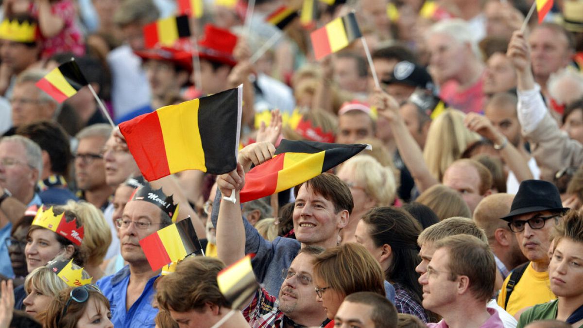 People wave Belgian flags as royal family members arrive outside of the national ball in the Marolles district of Brussels on Saturday, July 20, 2013.