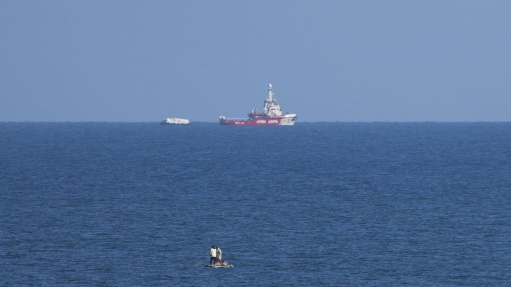 A ship belonging to the Open Arms aid group approaches the shores of Gaza towing a barge with 200 tons of humanitarian aid.
