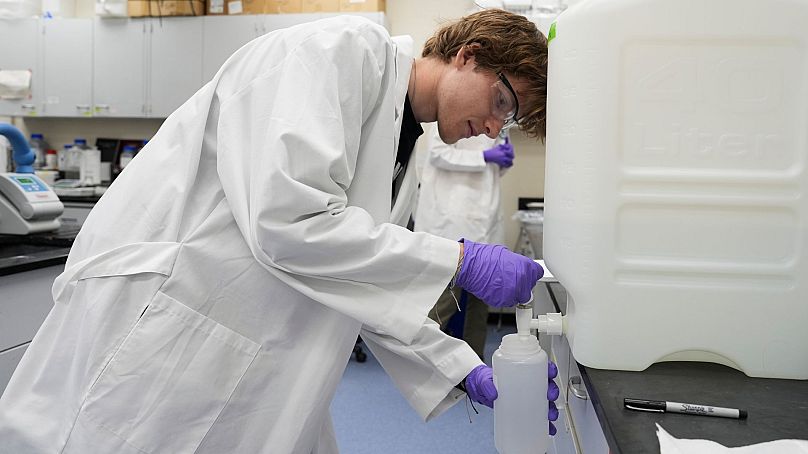 Logan Feeney verse un échantillon d'eau PFAS dans un récipient à des fins de recherche, le 10 avril 2024, dans un laboratoire de l'Agence américaine de protection de l'environnement à Cincinnati.