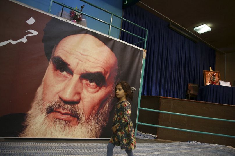Sur cette photo du mardi 22 janvier 2019, une jeune fille passe devant une affiche de l'ayatollah Ruhollah Khomeini.