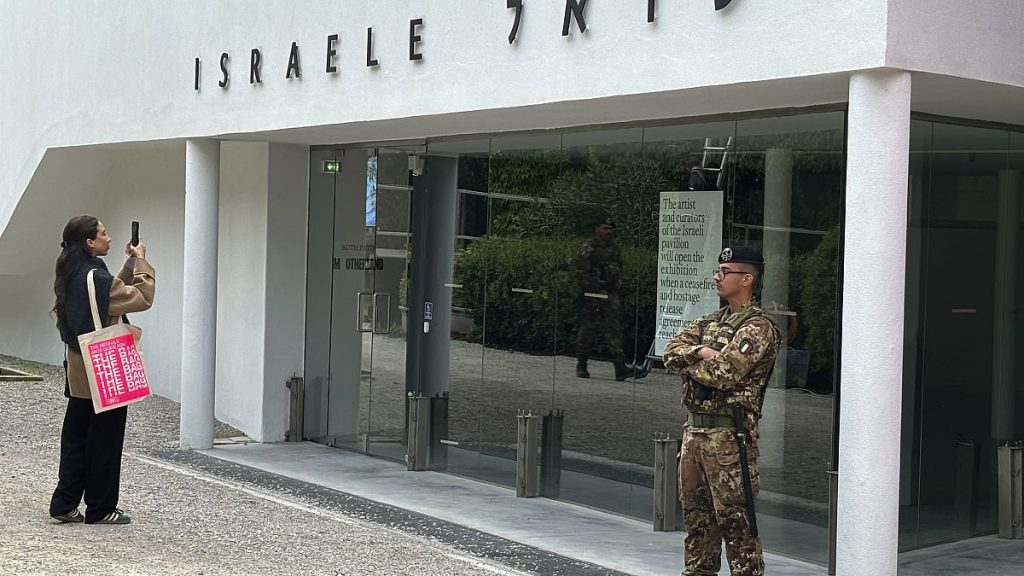 A woman takes a photo as an Italian soldier patrols the Israeli national pavilion at the Biennale contemporary art fair in Venice, Italy, Tuesday, April 16, 2024.