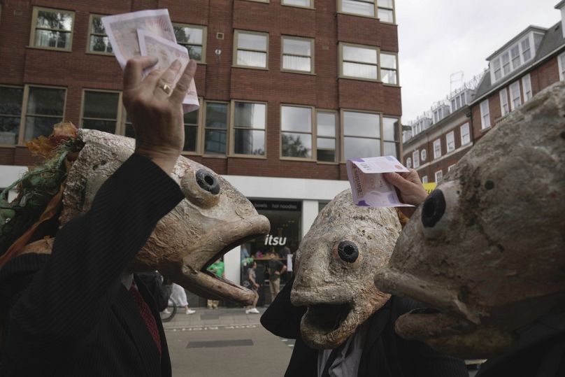 Des manifestants portent des masques de poisson alors qu'ils protestent devant le ministère de l'Environnement, de l'Alimentation et des Affaires rurales (DEFRA) contre la surpêche, à Londres, en septembre 2023.