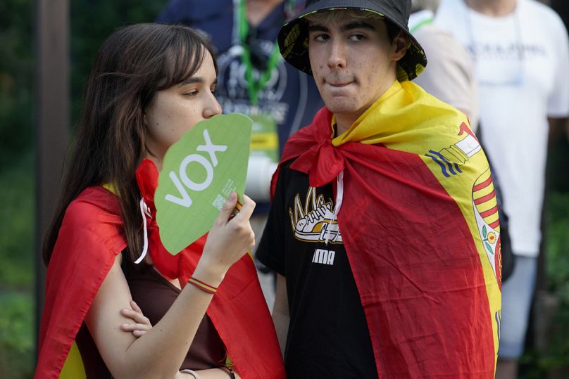 Des partisans du parti d'extrême droite Vox portant des drapeaux espagnols sur leurs épaules se tiennent devant le siège du parti à Madrid.
