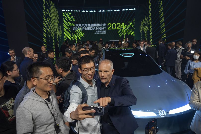 Les participants posent pour des photos à proximité des dernières voitures dévoilées lors d'un événement médiatique organisé par le groupe Volkswagen au salon de l'auto de Pékin.
