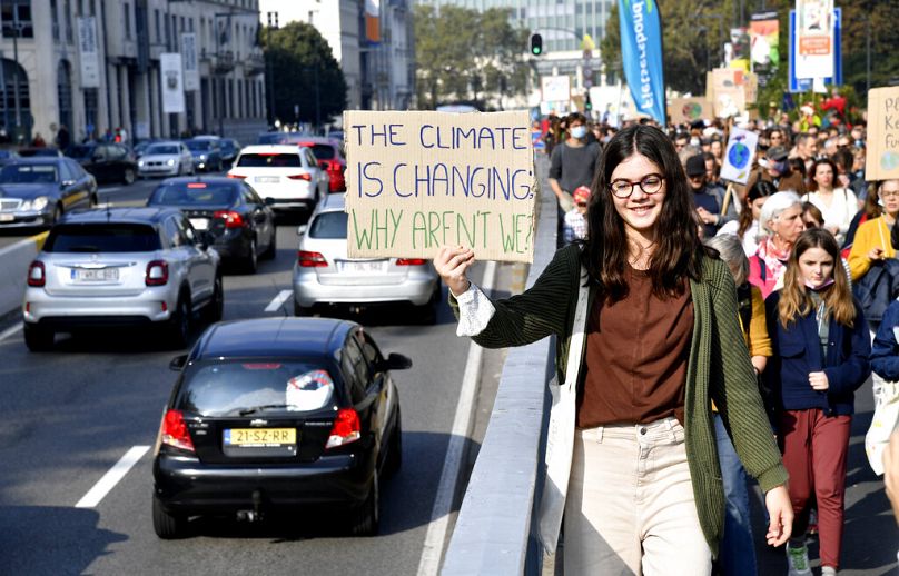 Une jeune fille brandit une pancarte indiquant la circulation venant en sens inverse alors qu'elle participe à une marche et une manifestation pour le climat à Bruxelles, en octobre 2021.