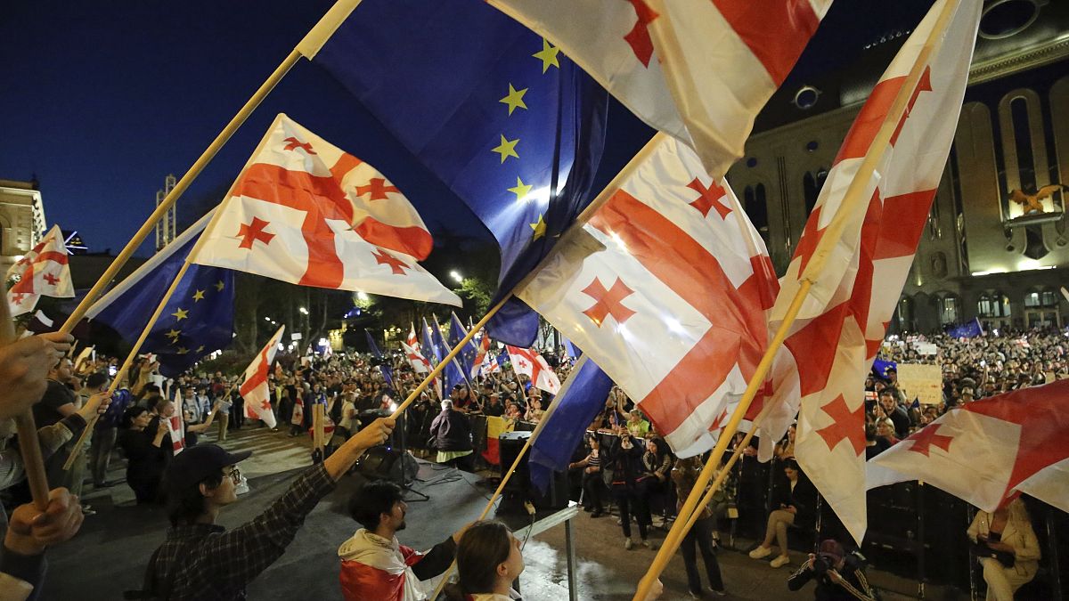 Demonstrators wave Georgian and EU flags as they gather outside the parliament building in Tbilisi on April 17, 2024