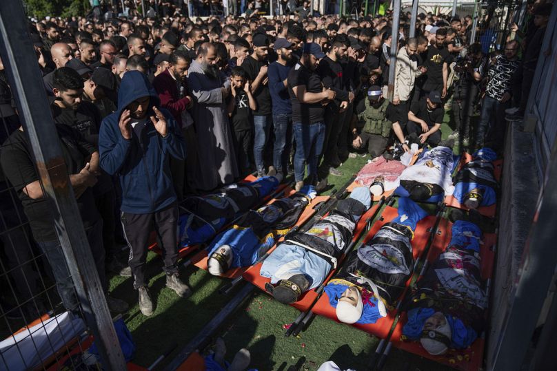 Les personnes en deuil prient sur les corps des Palestiniens, drapés dans les drapeaux du groupe militant du Jihad islamique, lors de leurs funérailles dans le camp de réfugiés de Nur Shams, près de la Cisjordanie.
