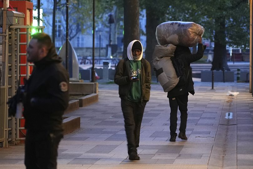 Des migrants quittent un campement de fortune après avoir été expulsés par des policiers, tôt mardi 23 avril 2024 à Paris.