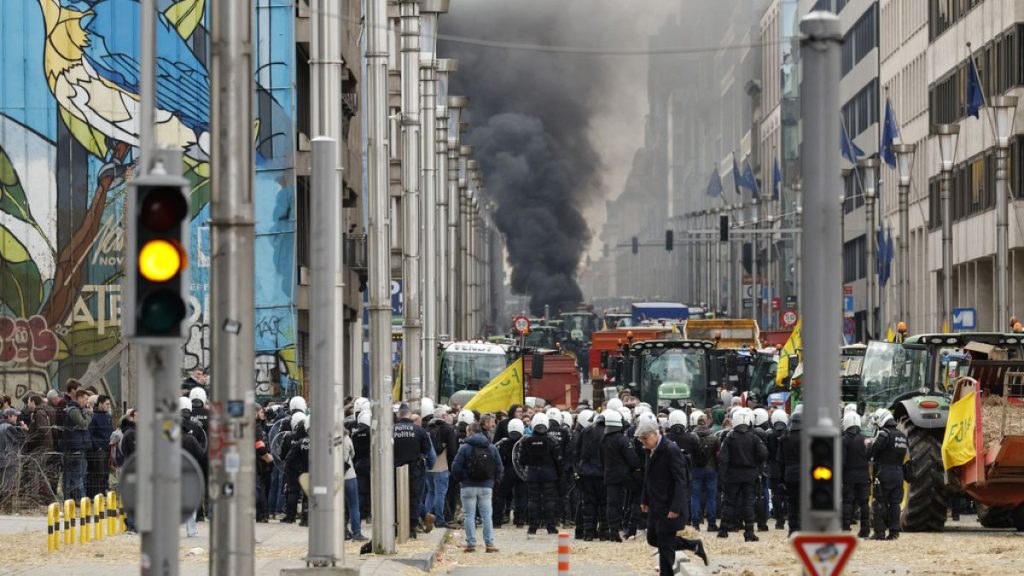 Police behind a barrier look at a pile of potatoes dumped by protestors during a demonstration of farmers near the European Council