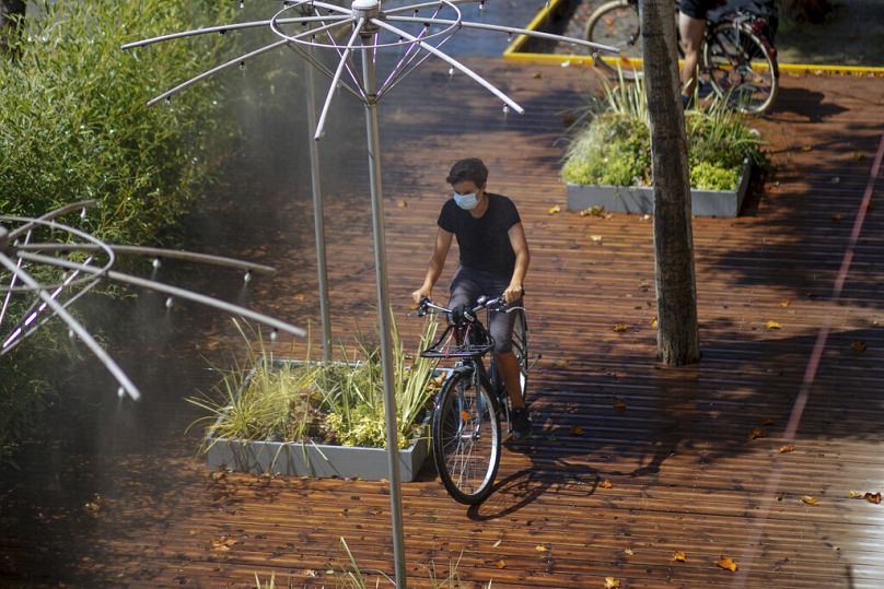 Un homme fait du vélo alors qu'il se rafraîchit sous une douche publique le long de la Seine à Paris, août 2020