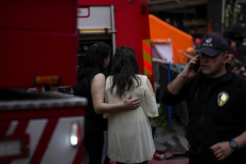 Deux femmes se rassemblent alors que les pompiers et les équipes d'urgence travaillent à la suite d'un incendie dans une discothèque à Istanbul, en Turquie, le mardi 2 avril 2024.