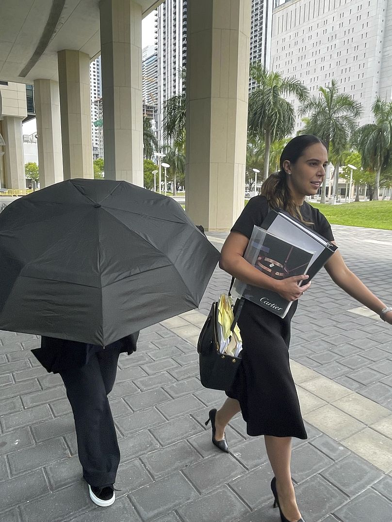 La célèbre créatrice de sacs à main Nancy Gonzalez se cache sous un parapluie alors qu'elle se promène avec son avocat Andrea Lopez devant le palais de justice fédéral, le lundi 22 avril 2024, à Miami.