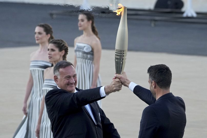Tony Estanguet, président de Paris 2024, à droite, reçoit la flamme olympique des mains de Spyros Capralos, président du Comité olympique grec, à Athènes, le vendredi 26 avril 2024.