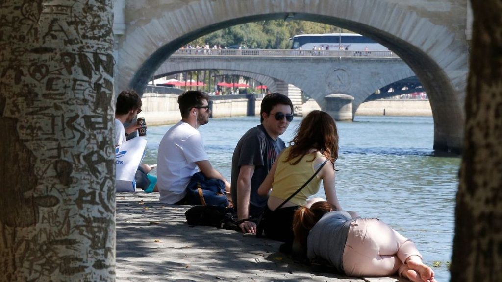 People rest by the bank of the River Seine during a heatwave in summer 2018.