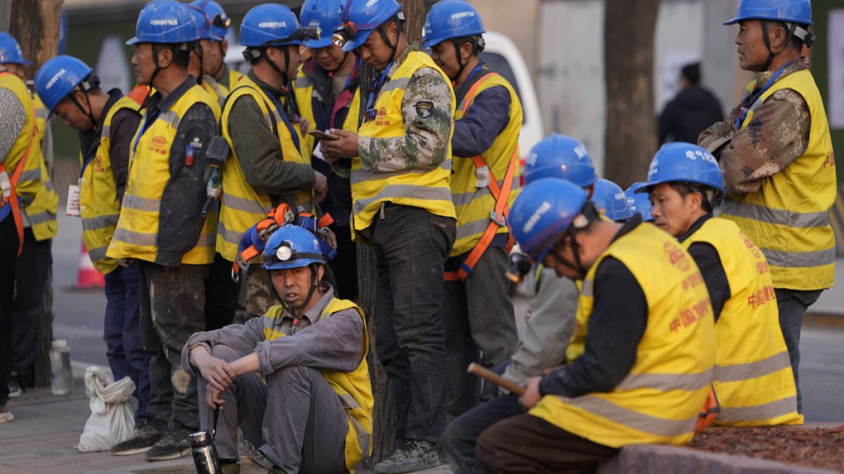 Workers wait for transport outside a construction site in Beijing, Tuesday, April 9, 2024.