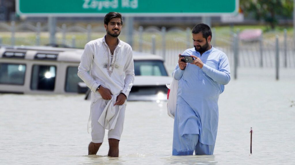 Two men walk through floodwater in Dubai.