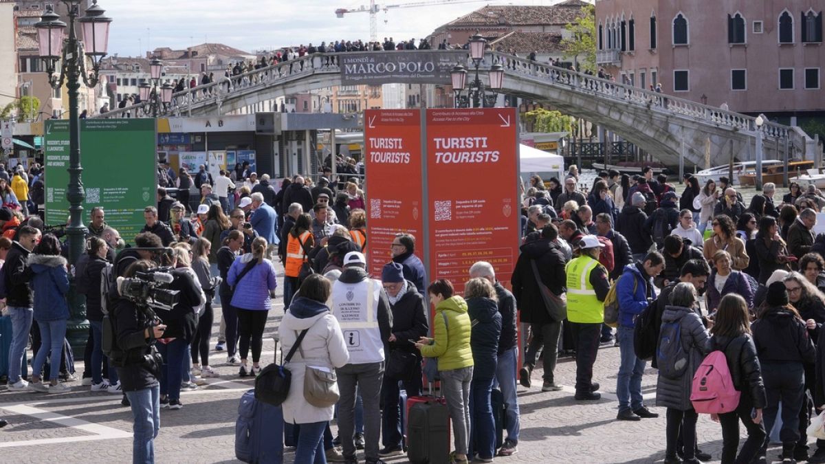 Stewards check tourists QR code access outside the main train station in Venice, Italy, 26 April 2024