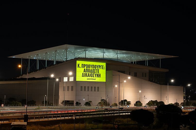 Les militants de Greenpeace Grèce projettent un message disant : Κ.  ΠΡΩΘΥΠΟΥΡΓΕ (Leaders mondiaux : nous vous observons) sur le centre de conférence SNFCC.