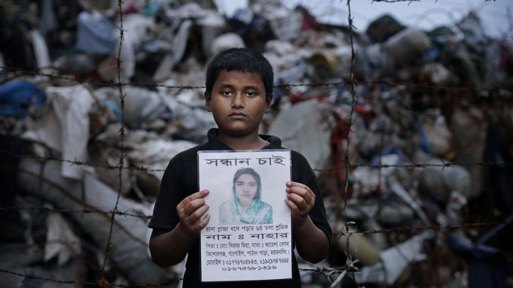 A family member holds a picture of a garment worker, victim of the 2013 Rana Plaza factory collapse
