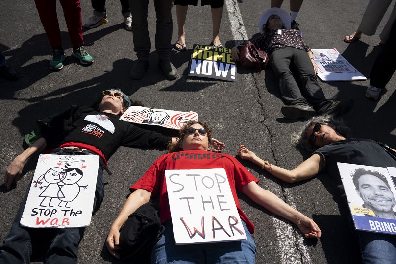 Des proches des otages détenus à Gaza et leurs partisans gisent sur la route pour bloquer la circulation à l'extérieur du bureau de l'ambassade américaine à Tel Aviv, Israël, le vendredi 12 avril 2024.