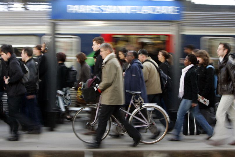 Un banlieusard marche avec son vélo à côté d'un train à Saint Lazare à Paris, mars 2009