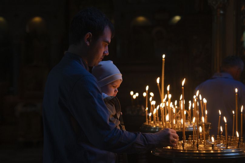 Des gens allument des bougies pendant qu'ils prient dans la cathédrale Saint-Volodymyr la veille de Pâques à Kiev, en Ukraine, le samedi 4 mai 2024.