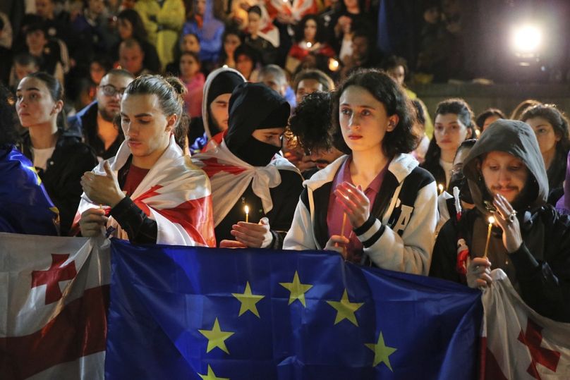 Des manifestants avec des drapeaux géorgiens et européens tenant des bougies se tiennent devant l'église de Kashveti lors d'une manifestation contre 
