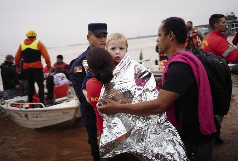 Un membre de la Défense civile porte un enfant sauvé d'une zone inondée par de fortes pluies à Porto Alegre, dans l'État de Rio Grande do Sul, au Brésil, le samedi 4 mai 2024.