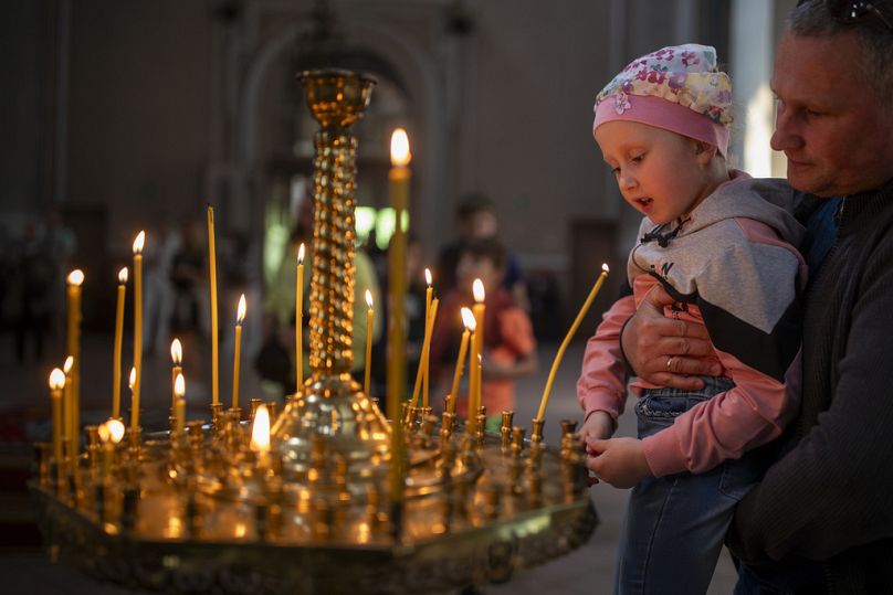 Des croyants allument des bougies après une cérémonie de bénédiction d'un gâteau et d'un œuf de Pâques à l'église orthodoxe du Saint-Esprit à Vilnius, en Lituanie, le samedi 4 mai 2024.