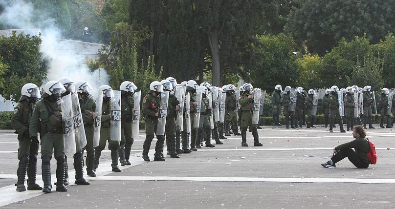 Un manifestant assis par terre devant la police anti-émeute dans le centre d'Athènes, le mardi 9 décembre 2008.