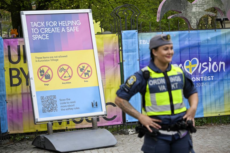 Un agent de sécurité se tient devant un panneau d'information au village de l'Eurovision dans le parc Folkets, à Malmö, en Suède, en mai 2024.