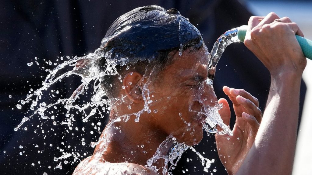 A man pours water from a pipe over himself on a hot day in Manila, Philippines.