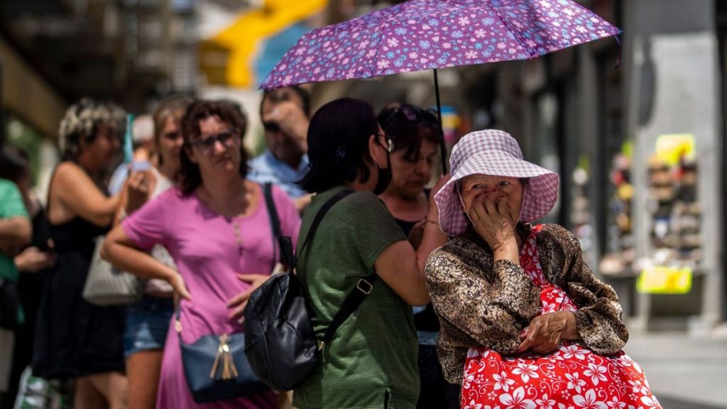A woman queues to buy lottery tickets during a hot day in Madrid, July 2022 - Spain