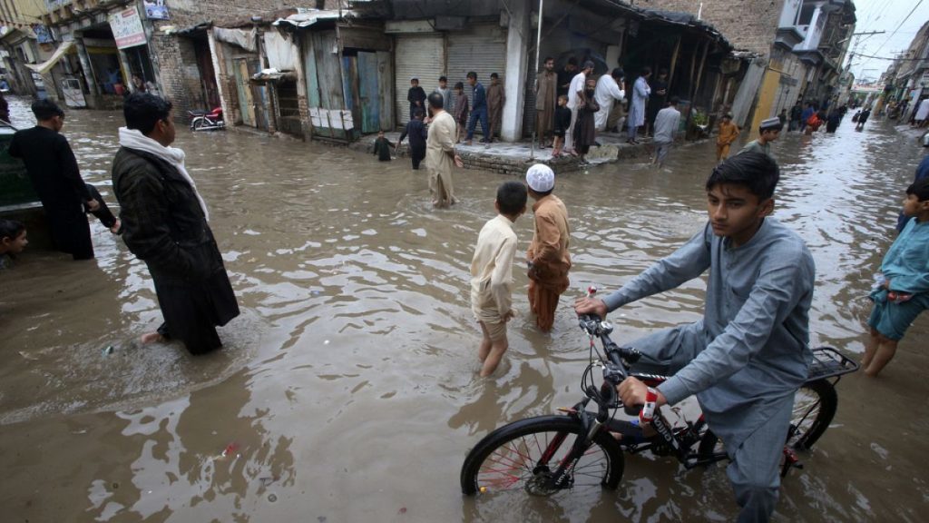 Youngsters wade through a flooded street caused by heavy rain in Peshawar, Pakistan in April