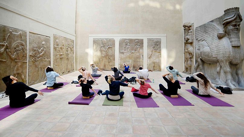 Un groupe s'exerçant sur des tapis de yoga dans la cour de Khorsabad du Louvre
