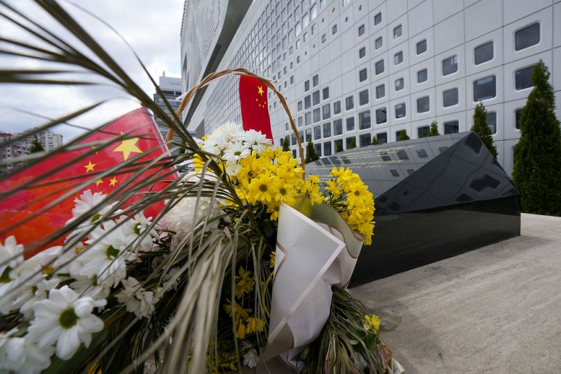 Un drapeau chinois est placé près de fleurs sur un monument sur le site d'une ancienne ambassade de Chine à Belgrade, en Serbie, le samedi 4 mai 2024.