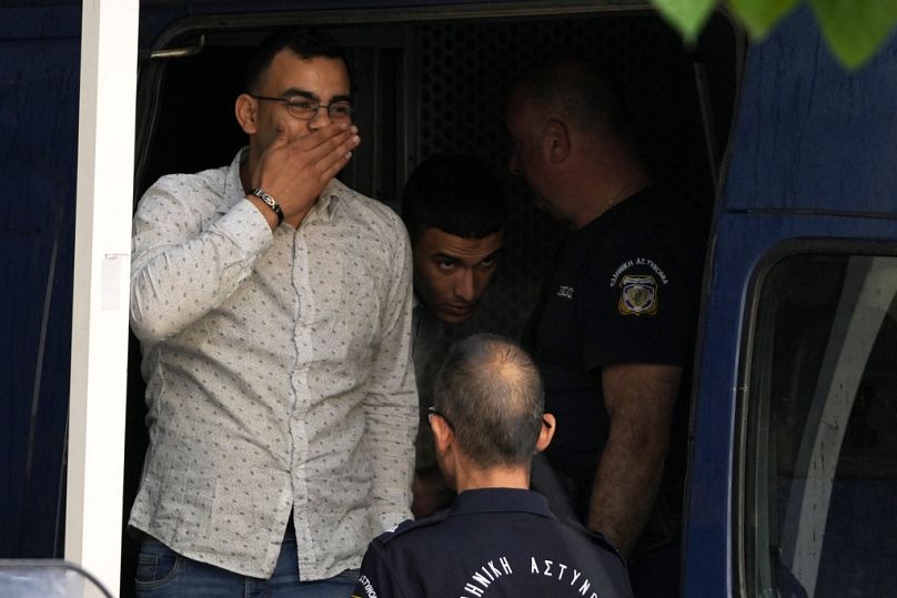 L'un des neuf Égyptiens accusés d'avoir causé le naufrage qui a tué des centaines de migrants salue alors qu'il est conduit par la police vers un palais de justice à Kalamata, le mardi 21 mai 2024.
