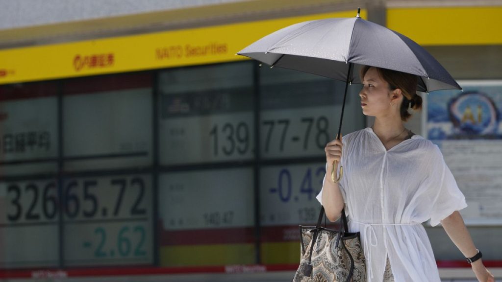 A woman walks across an intersection near monitors showing Japan