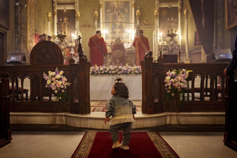 Une petite fille joue lors d'un service religieux orthodoxe de Pâques à la cathédrale arménienne de Bucarest, en Roumanie, le samedi 4 mai.