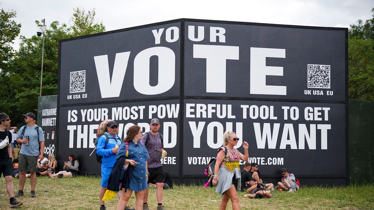 Festival goers walk past a sign that reads