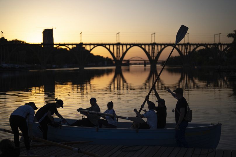 Des Ukrainiens, dont quelques-uns ont été déplacés de Marioupol pendant la guerre, s'entraînent à l'aviron sur le fleuve Dnipro au coucher du soleil, à Dnipro, mai 2024.