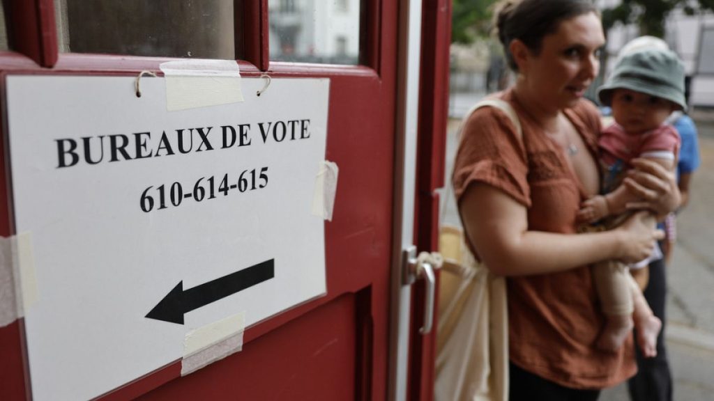 A woman holds her child outside a voting station in Strasbourg, eastern France, Sunday, June 30, 2024 (AP Photo/Jean-Francois Badias)