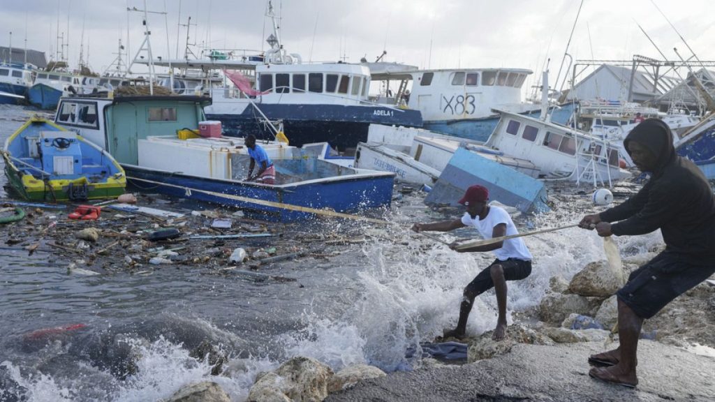 Fishermen pull a boat damaged by Hurricane Beryl back to the dock at the Bridgetown Fisheries in Barbados