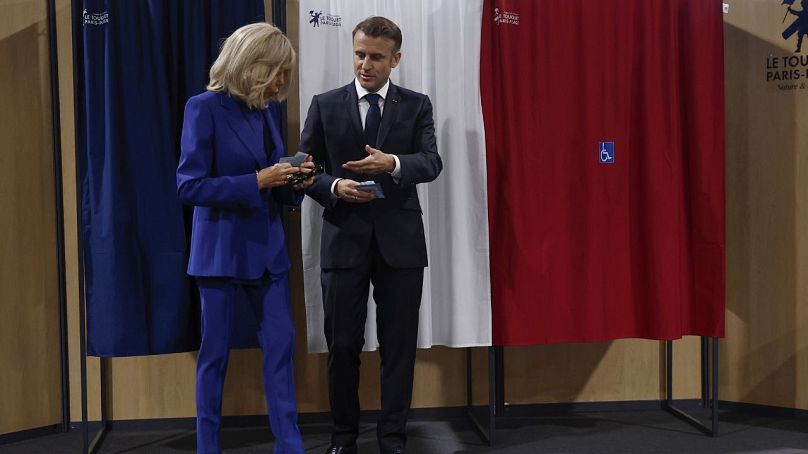 Le président français Emmanuel Macron et son épouse Brigitte Macron quittent l'isoloir avant de voter pour le second tour des élections législatives