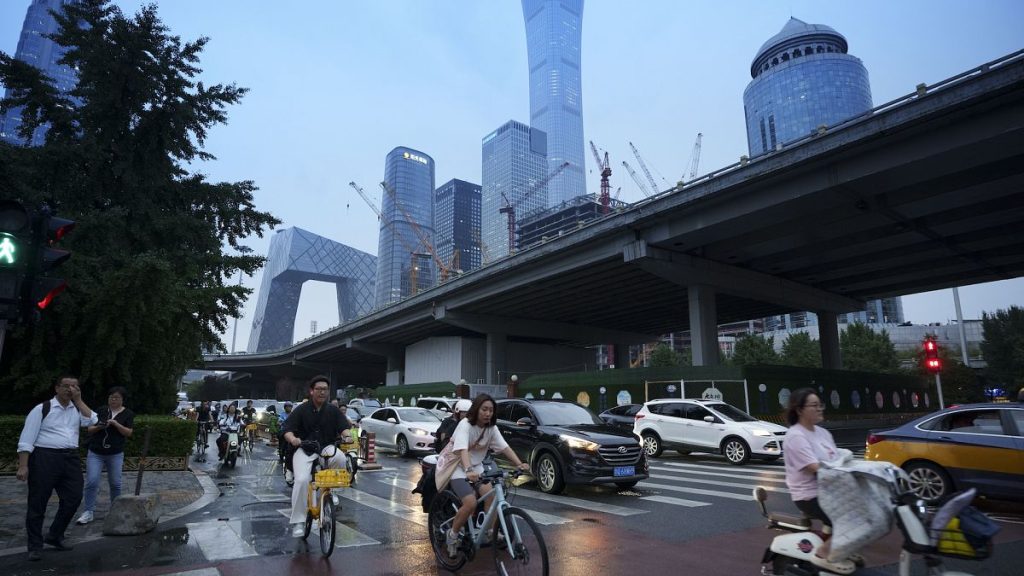 Pedestrians cross an intersection with the background of the central business district in Beijing, July 12 2024