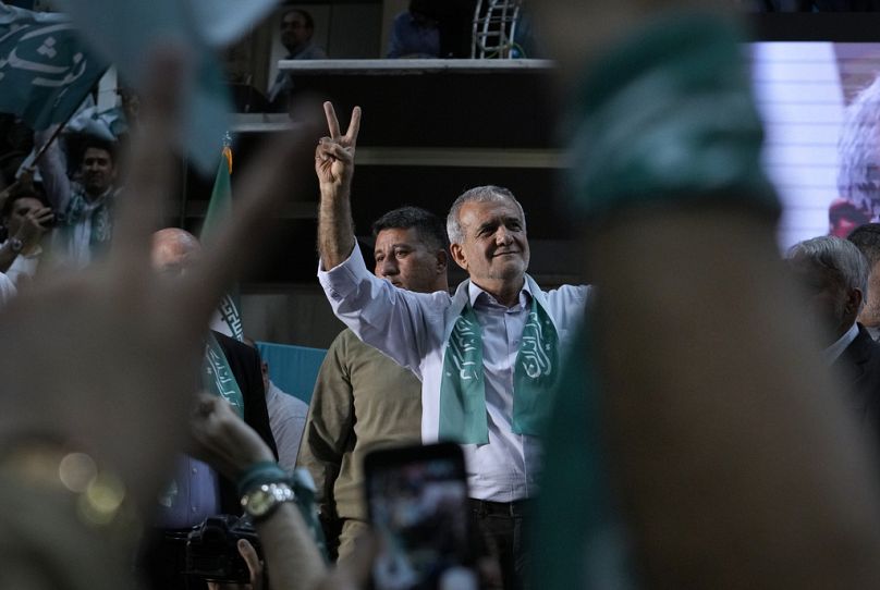 Le candidat iranien à la présidentielle Masoud Pezeshkian et ses partisans font le signe de la victoire lors d'une étape de campagne à Téhéran, le 23 juin 2024