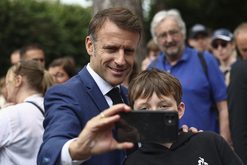 Le président français Emmanuel Macron prend un selfie avec un garçon après avoir voté au Touquet-Paris-Plage, dans le nord de la France, le dimanche 30 juin 2024.