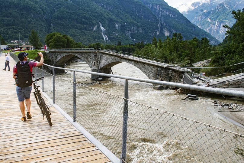 Un homme prend une photo du pont effondré de Visletto entre Visletto et Cevio, dans la vallée de la Maggia, le 30 juin 2024