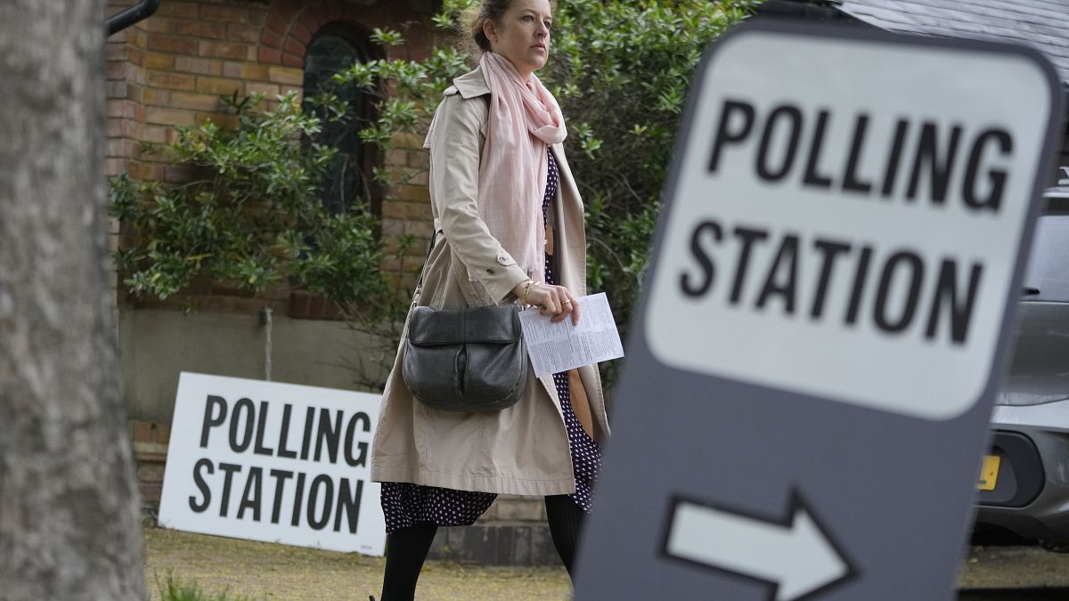 FILE - A woman holds her voting card as she arrives to vote in London in local elections, Thursday, May 2, 2024.